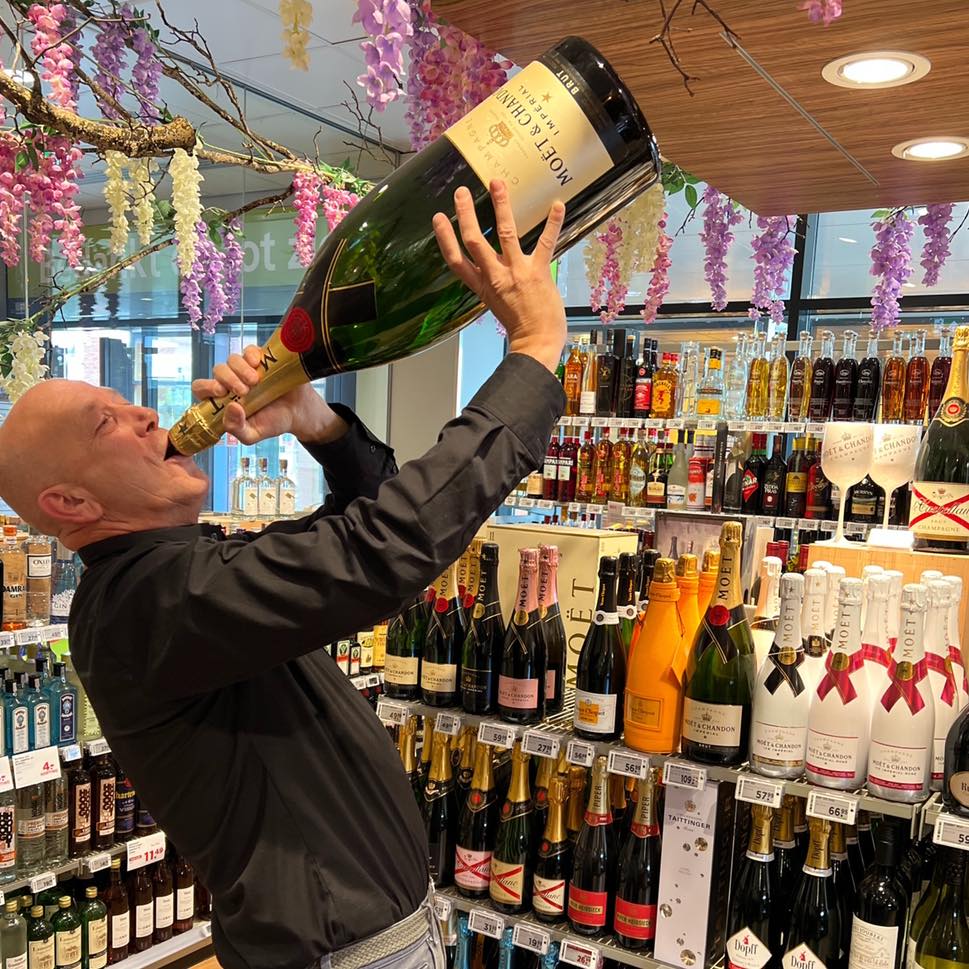 Peter, topslijter bij Slijterij PLUS Koelhuis in Bergschenhoek, met een grote fles